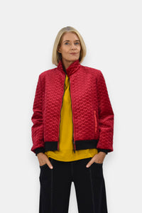 Woman wearing a red quilted jacket over a yellow top on a white background