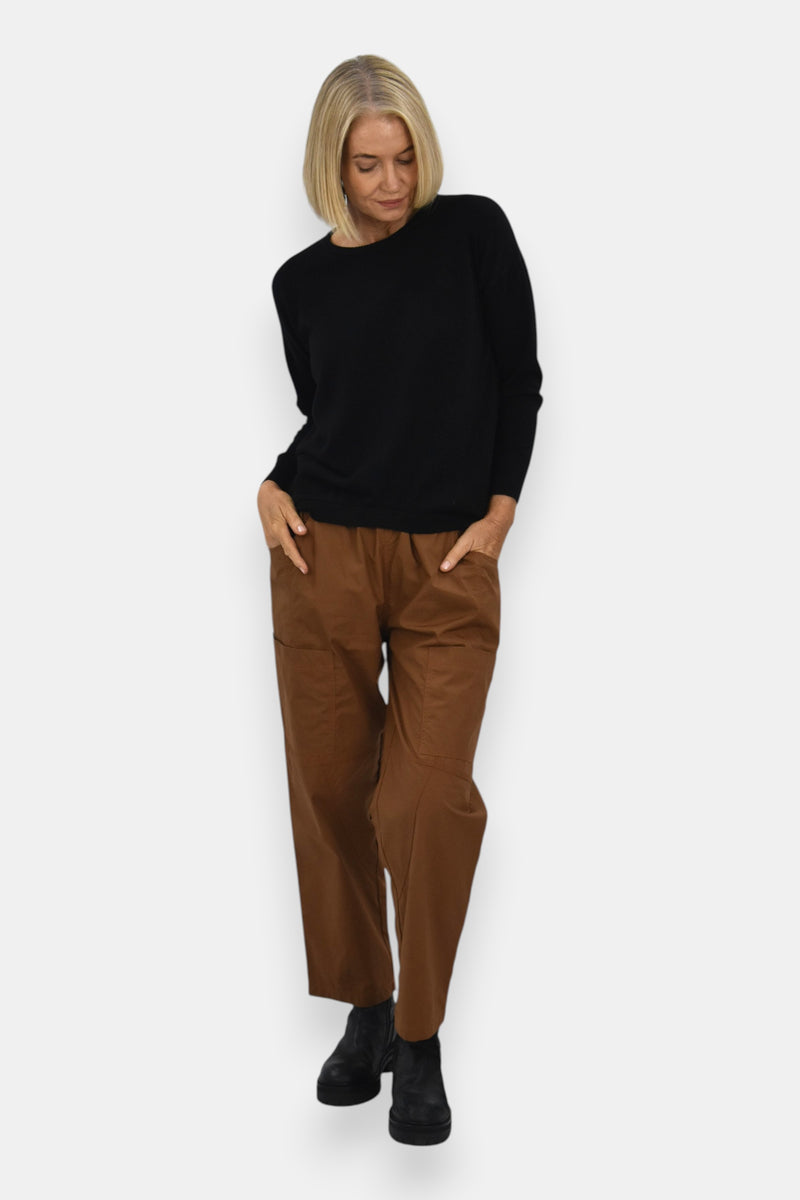 Woman wearing a black sweater and brown pants on a white background