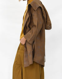 Woman wearing a brown coat over a mustard yellow outfit on a white background