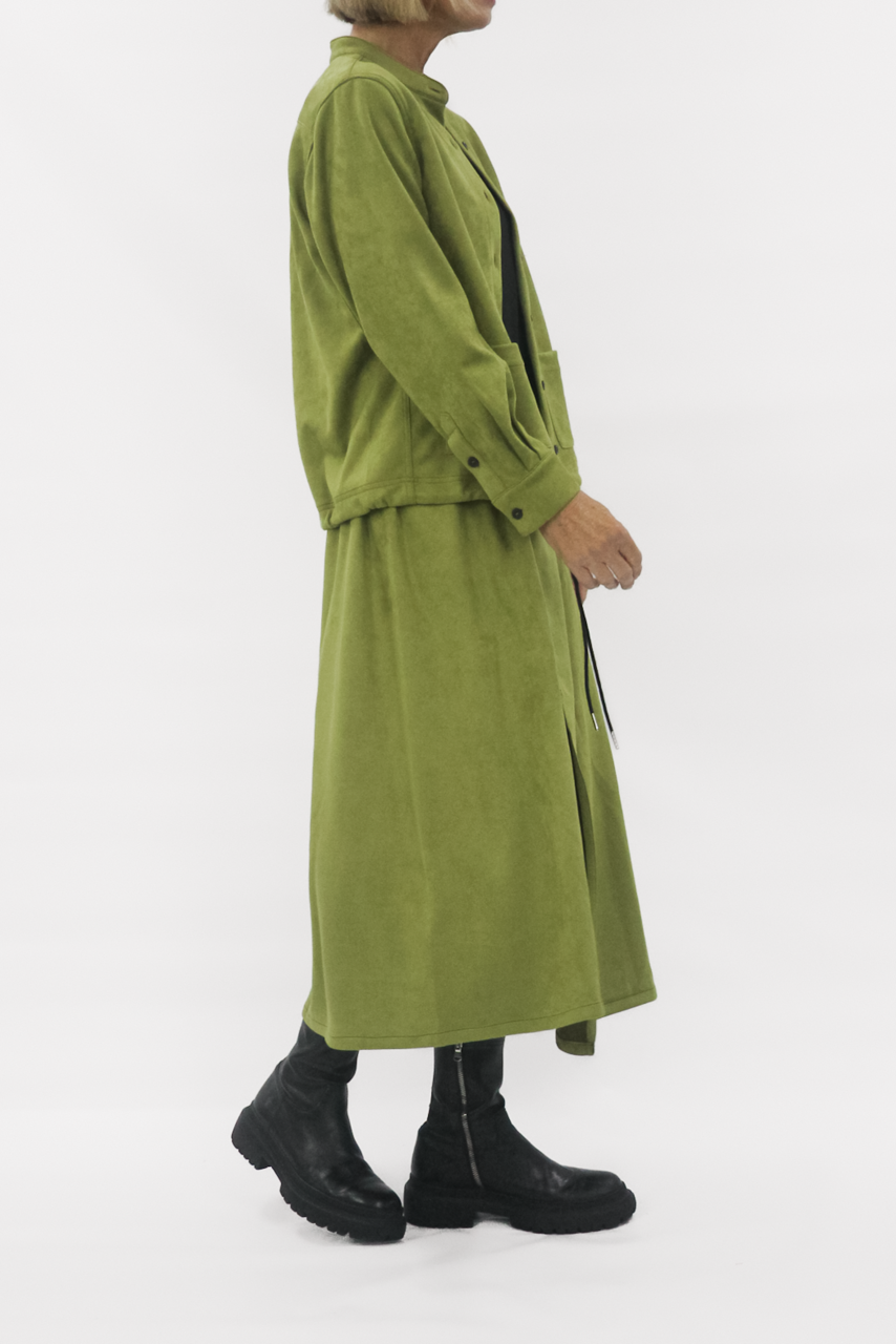 Person wearing a green jacket and skirt on a white background