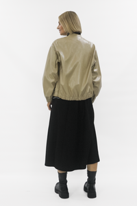 Person wearing a beige bomber jacket and black skirt on a white background